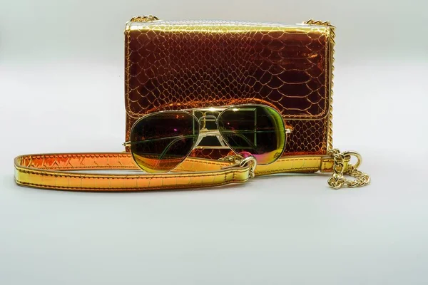 Retro clutch handbag and aviator sunglasses in a white background