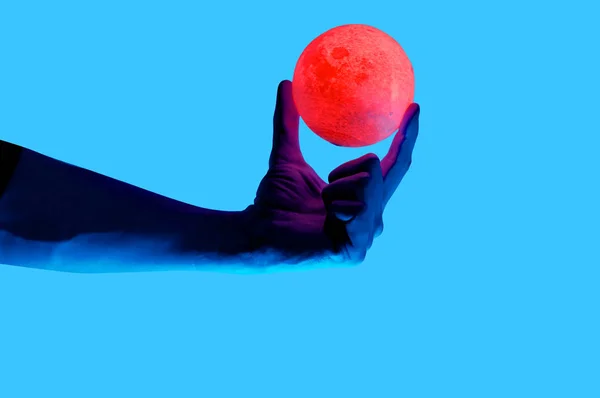 Kék háttér fotó ember tartja Hold alakja világító gömb elszigetelt. — Stock Fotó