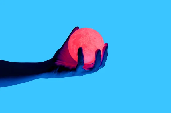 Aislado sobre fondo azul foto del hombre sosteniendo la forma de la luna esfera iluminada . — Foto de Stock