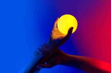 Sarı ay şeklindeki adam aydınlanmış küreyi tutuyor.