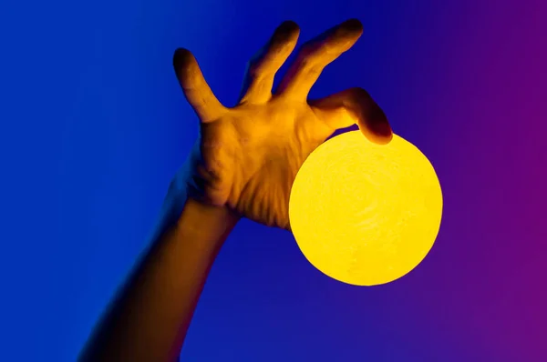 Sarı ay şeklindeki adam aydınlanmış küreyi tutuyor. — Stok fotoğraf