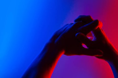 Renkli mavi, kırmızı, kontrast neon ışıklı eller. Elini gösteren adam.