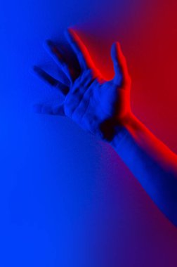 Renkli mavi, kırmızı, kontrast neon ışıklı eller. Elini gösteren adam.