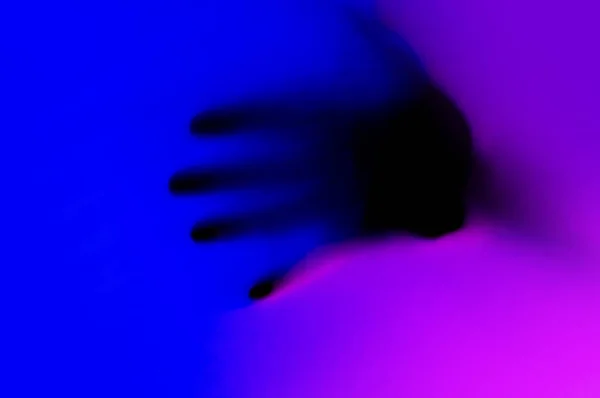 Hands in blue and pink neon light gradient behind white surface. — Stock Photo, Image