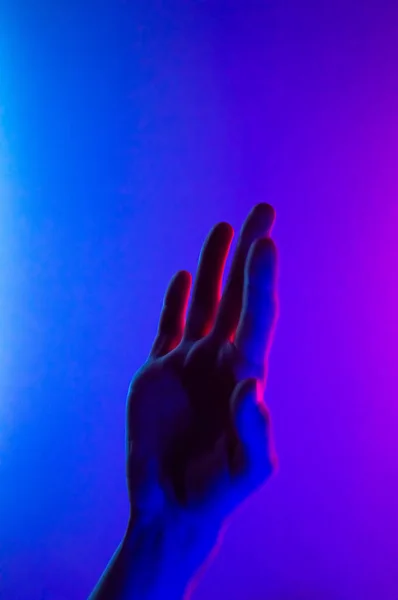 มือในสีฟ้าสีแดงความคมชัดแสงนีออน ผู้ชายที่แสดงอาการมือปาล์ม รูปแนวตั้ง เทรนดี้ปาร์ตี้คลับสไตล์แสงสว่าง . — ภาพถ่ายสต็อก