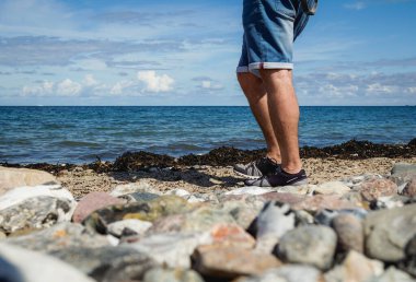 Heiligenhafen sahilinde şort giyen adam Baltık Denizi manzarasının tadını çıkarıyor. 