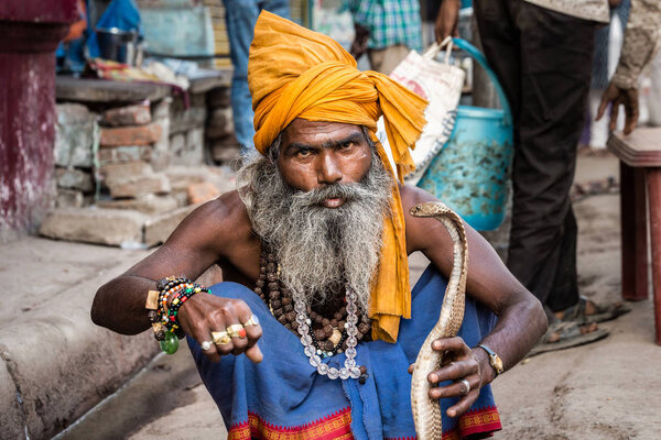 VARANASI, INDIA - MARCH 18, 2017: Holy man holding dangerous cobra snake in Varanasi, India.