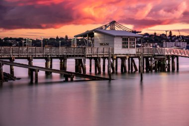 Auckland şehri, şehir merkezi ve Yeni Zelanda, Auckland 'ın ikonik simgesi Auckland Gökyüzü Kulesi ile fırtınanın ardından gün batımında ufuk çizgisi oluşturur..