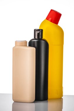 Deterjanlı plastik şişeler ve beyaz arka planda yansıması olan temizlik malzemeleri..