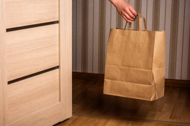 Karantina sırasında irtibatsız teslimat servisi. Karton el çantası teslim edildi ve kapının önüne bırakıldı..