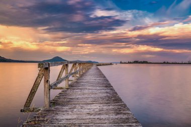 Old wooden wharf shot with long exposure during sunset. Location is Tokaanu Wharf located in Taupo region of North Island, New Zealand. clipart