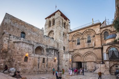 Turistler ve güvercinler Kudüs 'teki Kutsal Mezar Kilisesi' nin girişindeki bir meydanda yürüyüp oturuyorlar. Kudüs, İsrail - 19 Nisan 2018