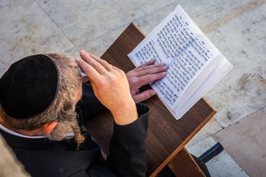 Yahudi ibadet eden kişi, Ağlama Duvarı 'nın yanında İbranice yazılmış kitabı okuyup namaz kılıyor. Dindar Yahudiler, Batı Duvarı yakınlarında Şabat 'ı kutluyor. Kudüs, İsrail. Kudüs, İsrail - 19 Nisan 2018