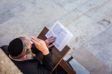 Yahudi ibadet eden kişi, Ağlama Duvarı 'nın yanında İbranice yazılmış kitabı okuyup namaz kılıyor. Dindar Yahudiler, Batı Duvarı yakınlarında Şabat 'ı kutluyor. Kudüs, İsrail. Kudüs, İsrail - 19 Nisan 2018