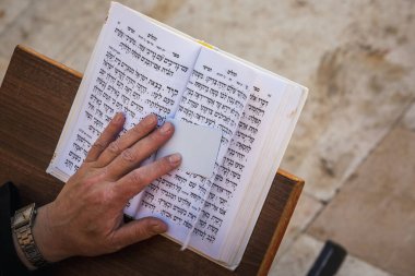 Yahudi ibadet edenin eli dua eder ve Ağlama Duvarı 'nın yanında İbranice yazılmış kitabı okur. Dindar Yahudiler, Batı Duvarı yakınlarında Şabat 'ı kutluyor. Kudüs, İsrail. Kudüs, İsrail - 19 Nisan 2018