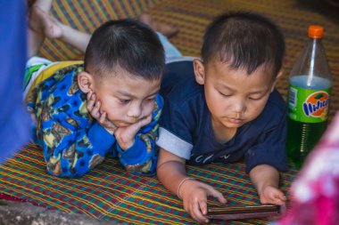 Yerel çocuklar Tayland 'ın Chiang Mai kentindeki ünlü uzun boyunlu köyünde telefonla oynuyorlar. Chiang Mai, Tayland - 05 Kasım 2017.