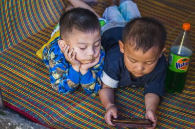 Yerel çocuklar Tayland 'ın Chiang Mai kentindeki ünlü uzun boyunlu köyünde telefonla oynuyorlar. Chiang Mai, Tayland - 05 Kasım 2017.