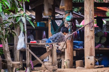 Buralı bir çocuk, hamakta, ayaklıkların üzerinde bir evde. Chiang Mai, Tayland - 12 Kasım 2017.