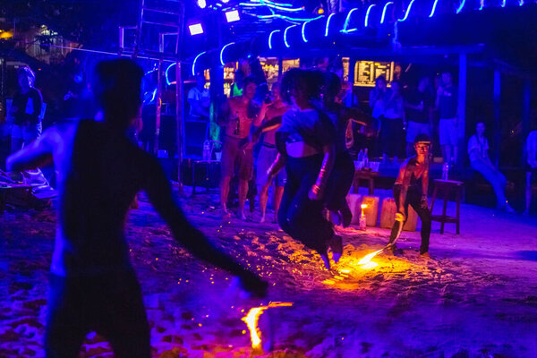 Туристы ночью прыгают через огненную веревку на пляже Таиланда. Ко Тао, Таиланд - 30 ноября 2017
.