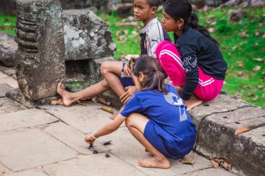 Yerel çocuklar Angkor Wat 'ta böceklerle oynuyorlar. Siem Reap, Kamboçya - 19 Kasım 2017.