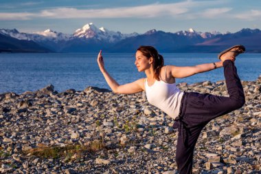 Kız, Pukaki Buzul Gölü 'nde turkuaz mavi su ve dağ manzarasıyla yoga yapıyor. Aoraki 'deki Pukaki Gölü - Cook Dağı Ulusal Parkı, Yeni Zelanda. Cook Dağı, Yeni Zelanda - 23 Aralık 2017.