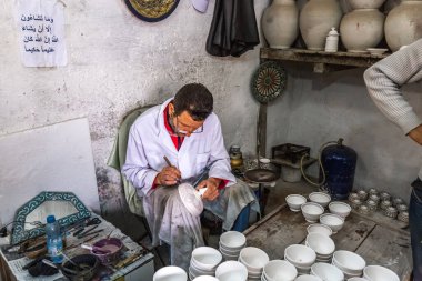 Yerel bir esnaf, eski Medine pazarında el yapımı eşyalar yapıyor. Fes, Fas - 10 Nisan 2016.