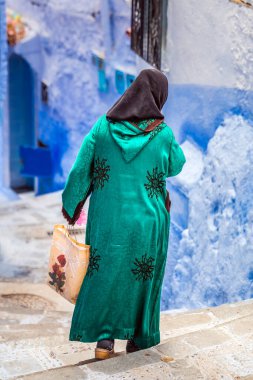 Geleneksel kıyafetler giyen bir kadın ünlü mavi şehir olan Fas 'ta yürüyor..