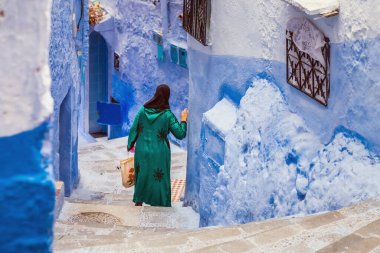Geleneksel kıyafetler giyen bir kadın ünlü mavi şehir olan Fas 'ta yürüyor..