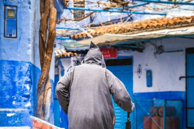 Geleneksel kıyafetler giyen bir adam ünlü mavi şehir olan Fas 'ta yürüyor..