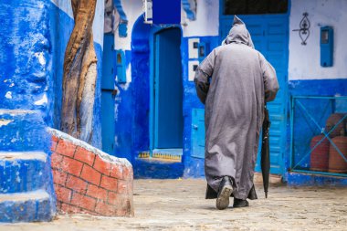 Geleneksel kıyafetler giyen bir adam ünlü mavi şehir olan Fas 'ta yürüyor..
