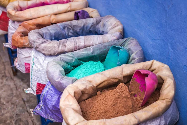 Şef Chaouen 'de satılık çuvallarda renkli toz pigmentleri. Fas 'ta mavi duvarları olan mavi bir şehir..