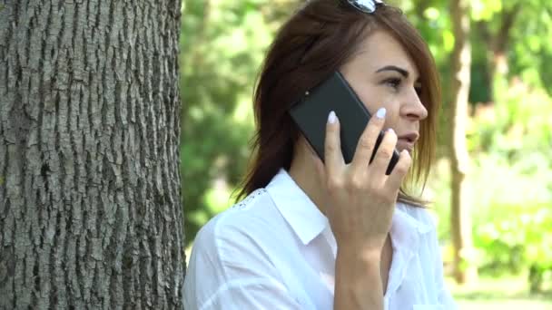 Junges Mädchen telefoniert auf dem Gras im Park — Stockvideo
