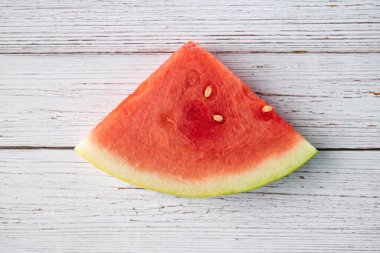 Dilimlenmiş karpuz meyvesi ahşap bir arka planda oturuyor.