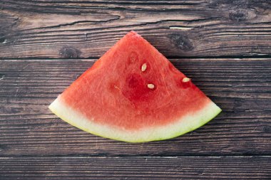 Dilimlenmiş karpuz meyvesi ahşap bir arka planda oturuyor.