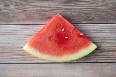 Dilimlenmiş karpuz meyvesi ahşap bir arka planda oturuyor.