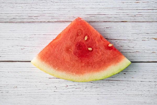 Dilimlenmiş karpuz meyvesi ahşap bir arka planda oturuyor.