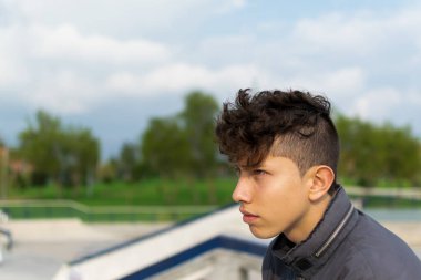 Açık yeşil gözlü, genç, yakışıklı bir İspanyol 'un portresi. Bogota, Kolombiya' da kaykay parkında gri bir ceket giyen harika bir saç kesimi.