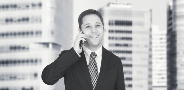 Businessman Talking On The Phone With Business City and Corporate Buildings In Background — Stock Photo, Image
