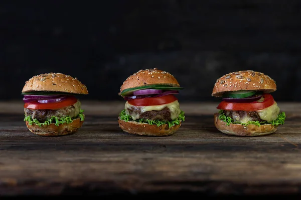 Hamburgerler Domatesler Soğanlar Salatalık Marul Erimiş Peynir Ahşap Bir Masada — Stok fotoğraf