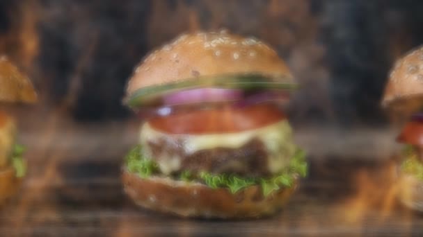 ハンバーガーは煙と燃える火に囲まれた素朴な木製の表面で提供しています 4Kアニメーションビデオ — ストック動画