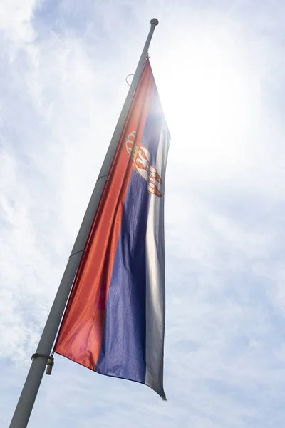 Serbian flag waving in the wind against white cloudy blue sky