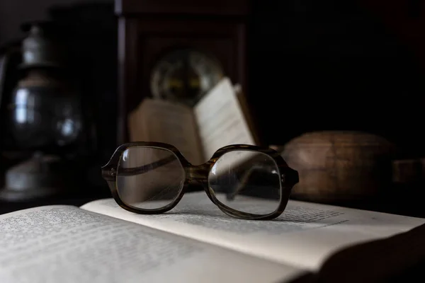 Old Worn Glasses Resting Opened Book Books Clock Background Reading — Stock Photo, Image
