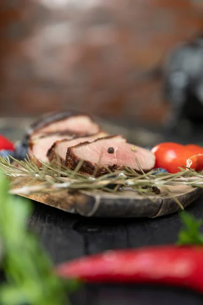 Goose breast Christmas roast with blueberries, tomatoes, red peppers and rosemary served on a wooden board