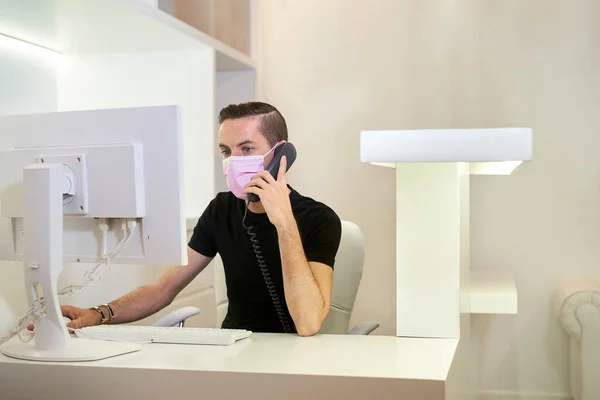 Receptionist who works in the reception of the dental, gynecological or aesthetic clinic. The receptionist takes a call. Medical concept. Horizontal photo.