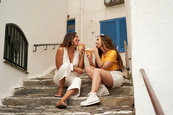 Dışarıda dondurma yiyen iki kız kardeş. Güzel bir köyün merdivenlerinde oturmuş dondurma yiyen ve gülen gençler..