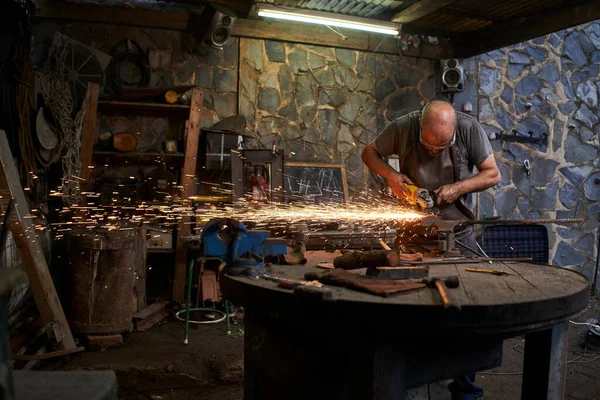 Eski bir nalbant dükkanında öğütücüyle çalışan bir işçi. Güvenlik gözlükleri ve eldivenlerle donatılmıştır.