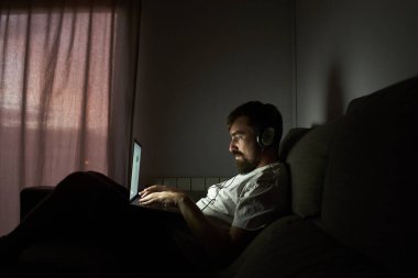 Adam geç saatlere kadar çalışıyor. Karanlıkta kanepede oturuyor..