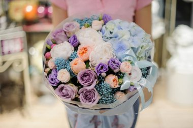 Büyük bir buket gül, peonies ve diğer güzel çiçekler oluşan mavi ve mor tonlarda tutan kadın