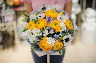 Düğünçiçeği ve diğer güzel çiçekler oluşan beyaz ve sarı tonlarda bir ihale çiçek kompozisyon tutan çiçekçi