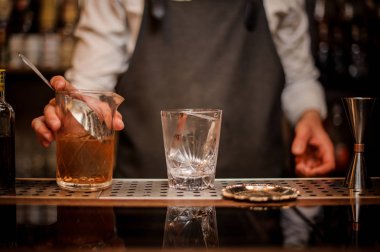 Profesyonel barmen karıştırma cam bir alkollü içki ve hazır ile kokteyl cam içine dışarı pourring holding